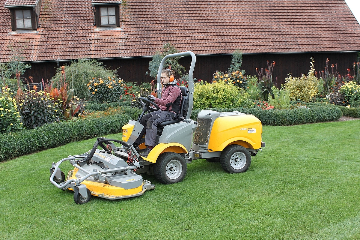 Junge Frau auf Aufsitzrasenmäher in den Gärten des Lehr- und Versuchshofs Tachenhausen