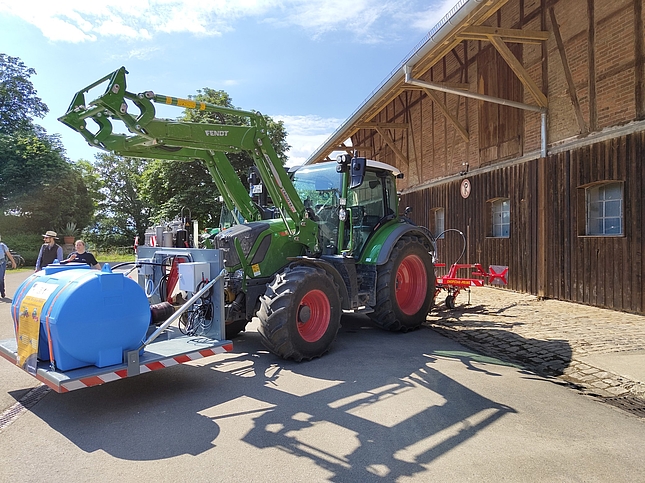 Traktor mit Wassertank auf Hebebühne vorne, linke Seitenansicht