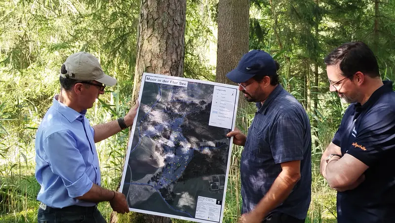 3 Personen mit einer Moorlandkarte im Wald