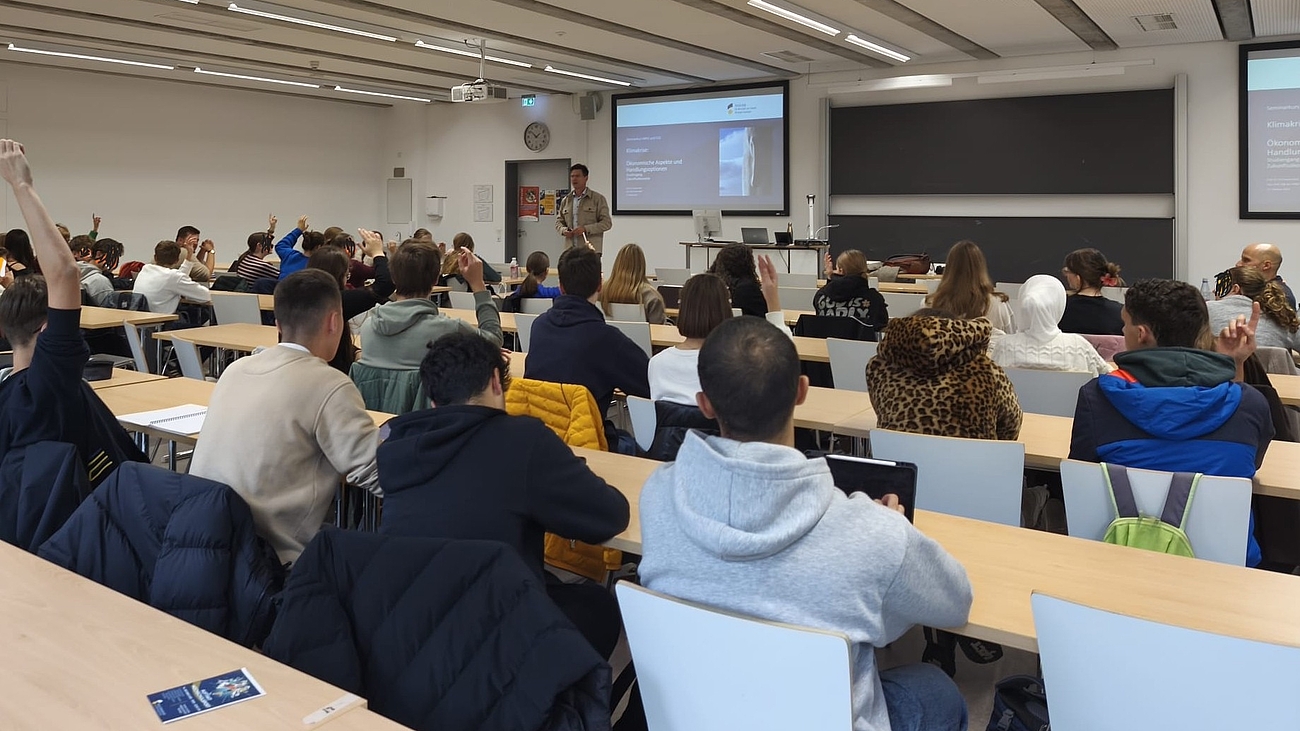 Blick von hinten in einen Hörsaal, voll besetzt mit Schüler:innen.