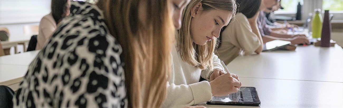 Studierende arbeiten an ihrem Tablet.