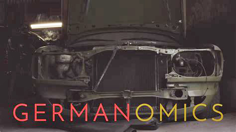 "Germanomics" Schriftzug, im Hintergrund Schrottauto